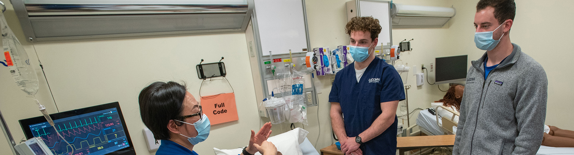 Students listen to instruction from a professor in a simulation lab.